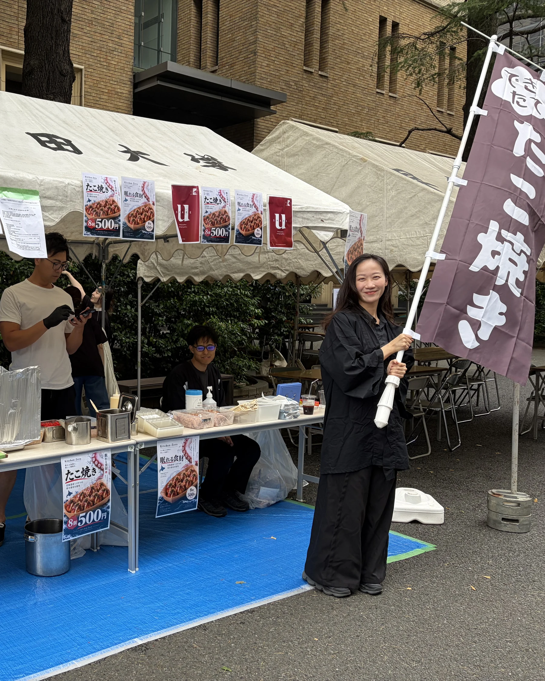早稻田地球感谢祭Kitchen Zero摊位前举着章鱼烧旗帜的工作人员