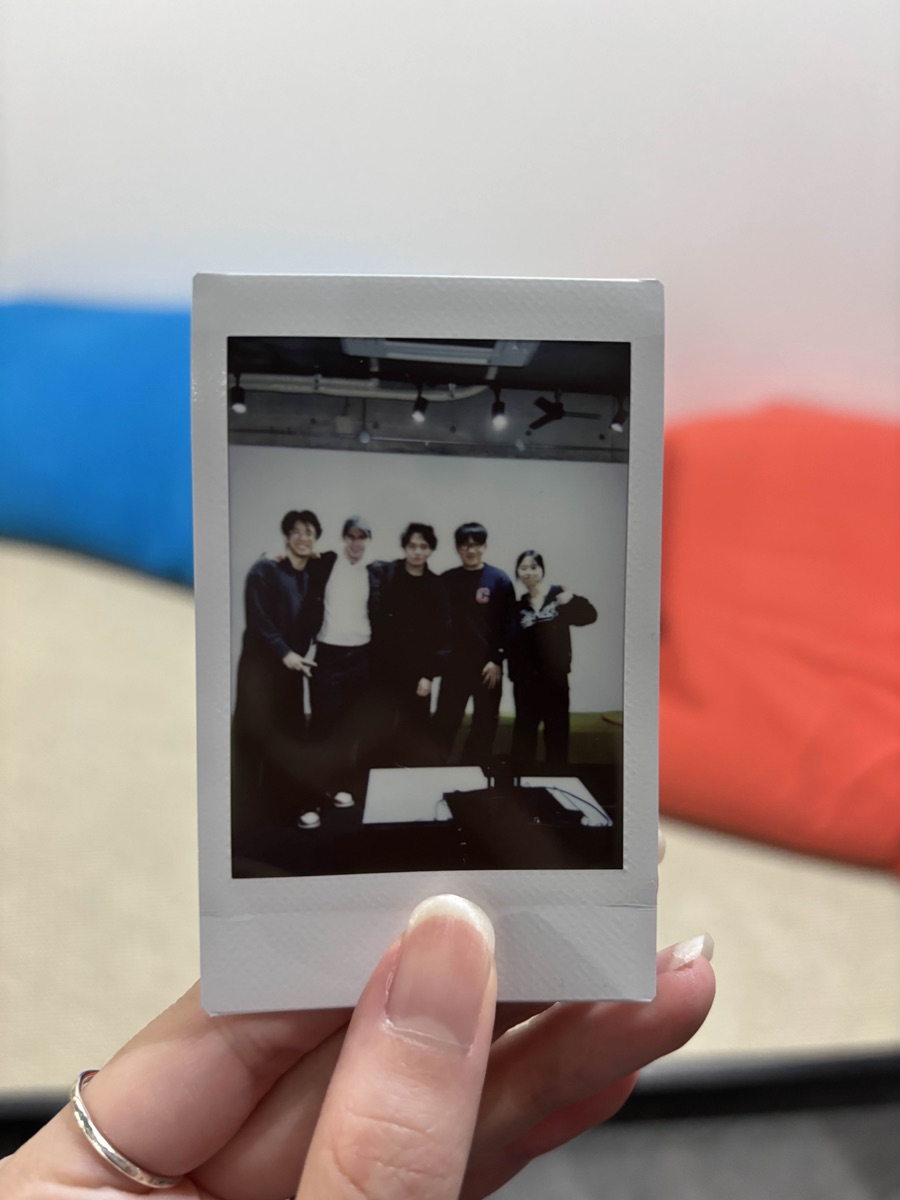 友人5人で写ったチェキプリントを手に持っている